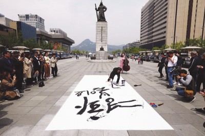 韩国书法家用毛笔字写下和平,春天,鲜花的字样,祈愿韩朝首脑会晤顺利